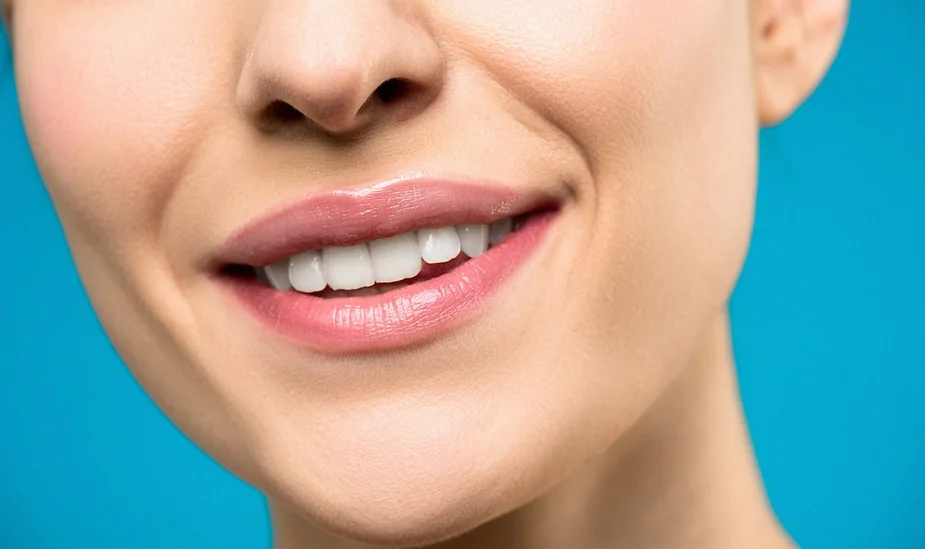 Primer plano de los labios y la sonrisa de una mujer sobre fondo azul