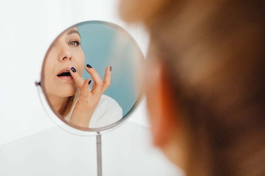 Mujer revisando sus labios en un espejo de tocador redondo