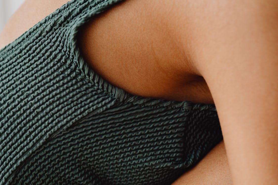 Primer plano de la axila de una mujer con vestido de baño verde