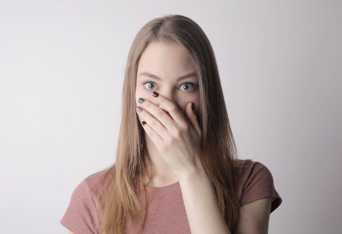 Surprised young woman covering her mouth with her hand