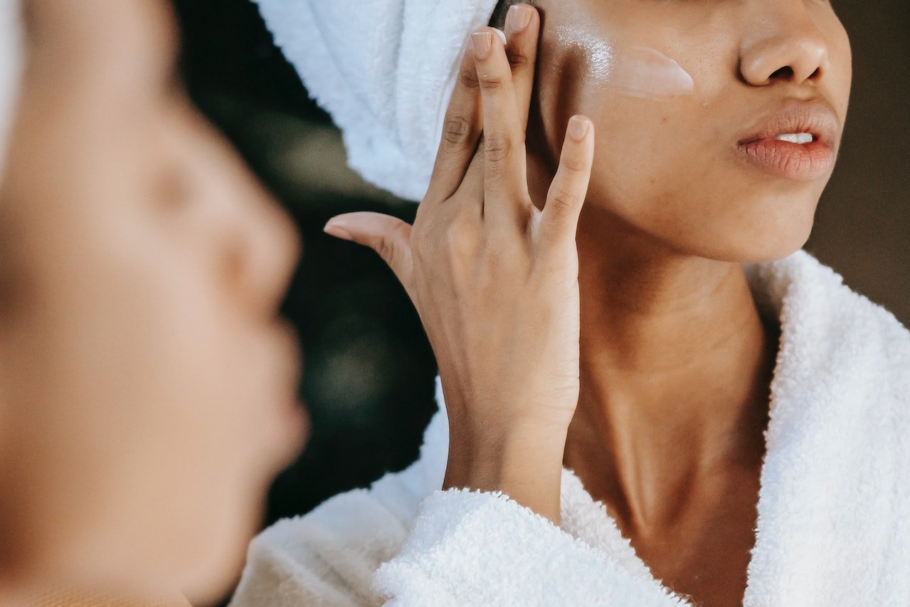 Woman applying cream to her cheekbone as part of her skincare routine
