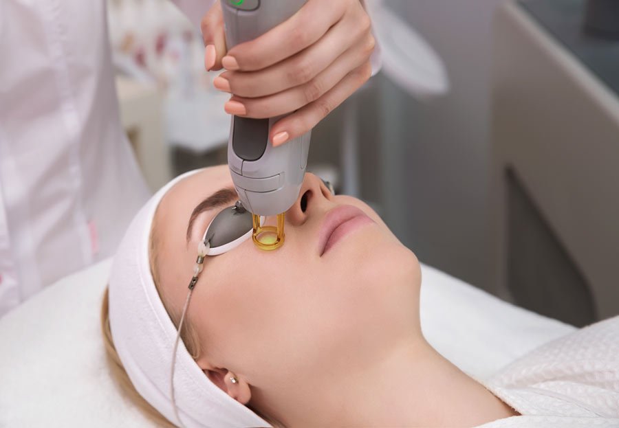 Paciente con gafas de protección durante un tratamiento con láser en el rostro