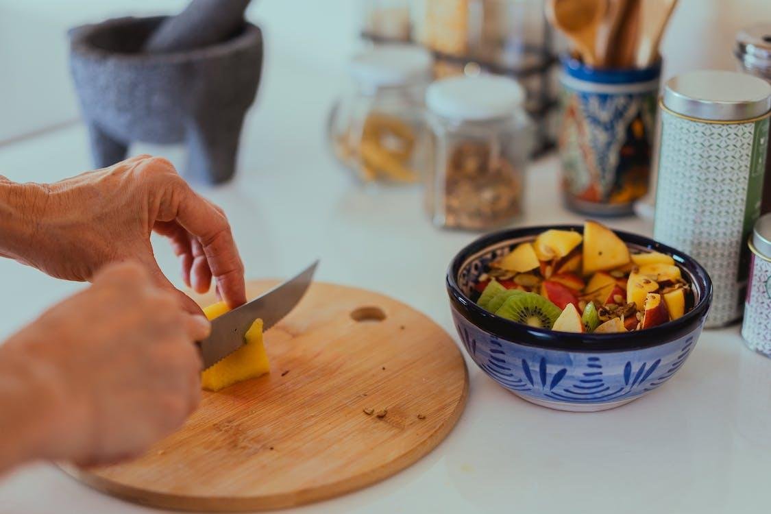 Persona preparando un plato de frutas frescas en la cocina