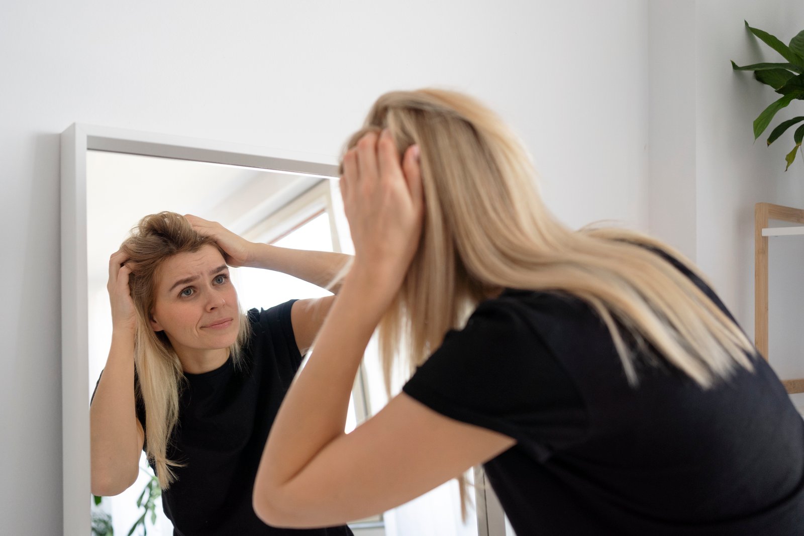 Medium shot confused woman looking mirror · ¿Cuáles son las causas de la dermatitis seborreica?