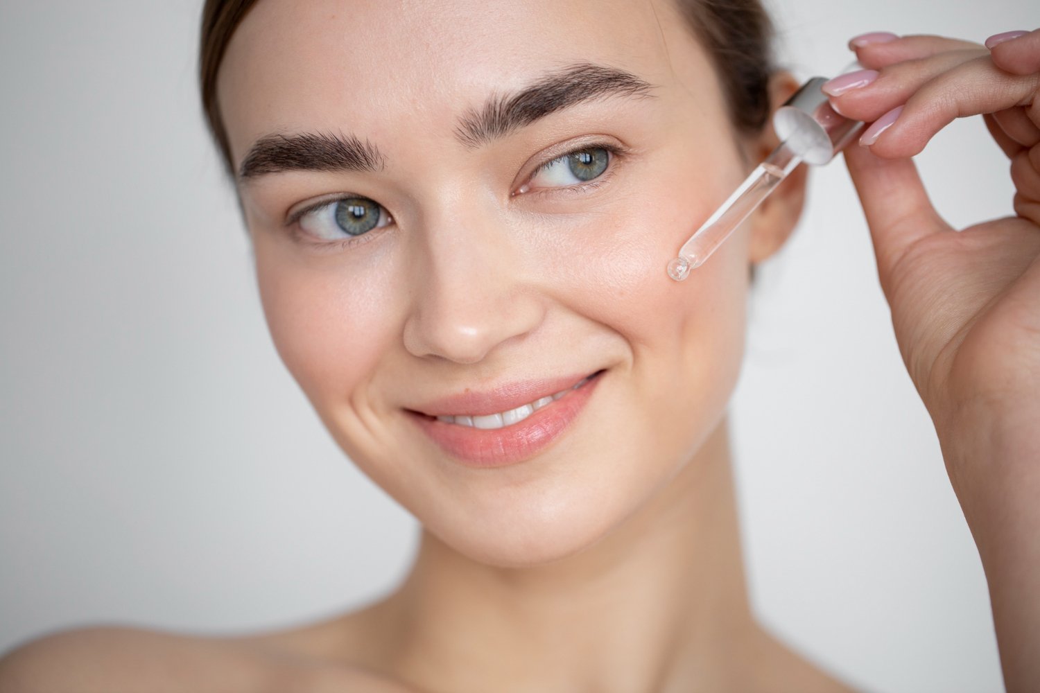 Mujer de piel clara aplicándose un sérum facial antiedad con gotero