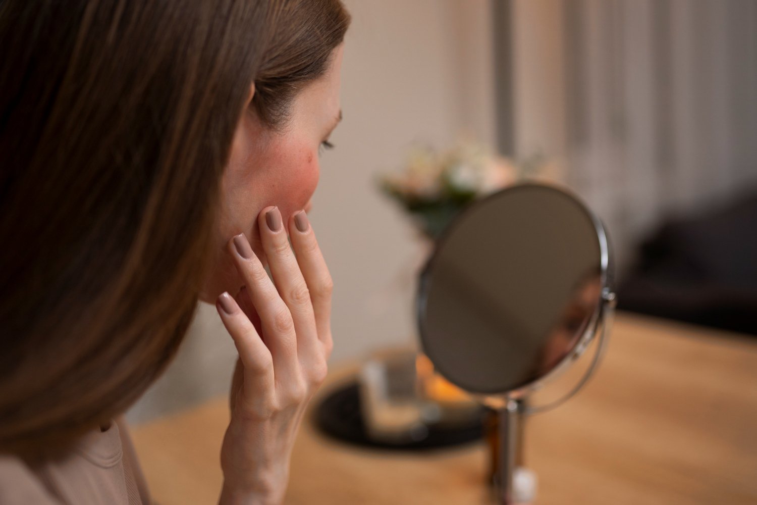 Woman looking her rosacea mirror 1 · ¿Cuáles son las consecuencias de no tratar la rosácea?