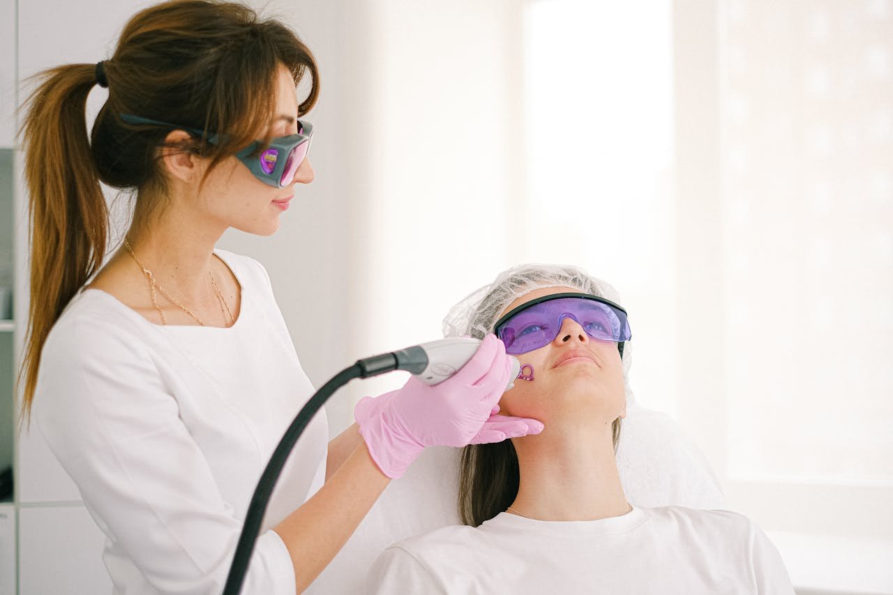 Profesional aplicando un tratamiento facial con un equipo de energía a una paciente recostada con gafas protectoras