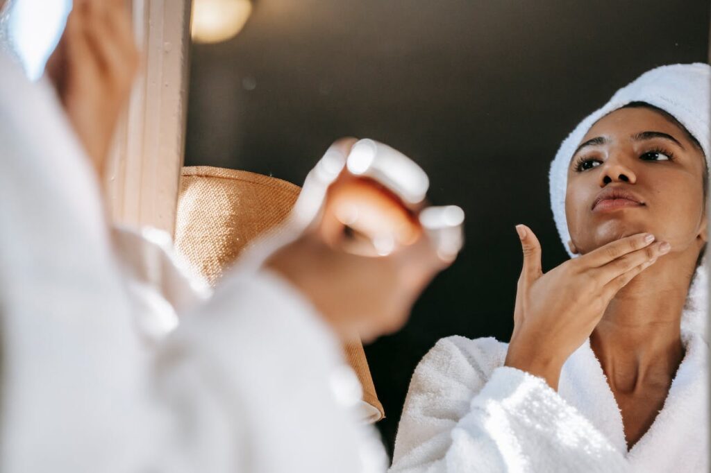 Mujer morena frente al espejo, aplicándose un exfoliante después del baño