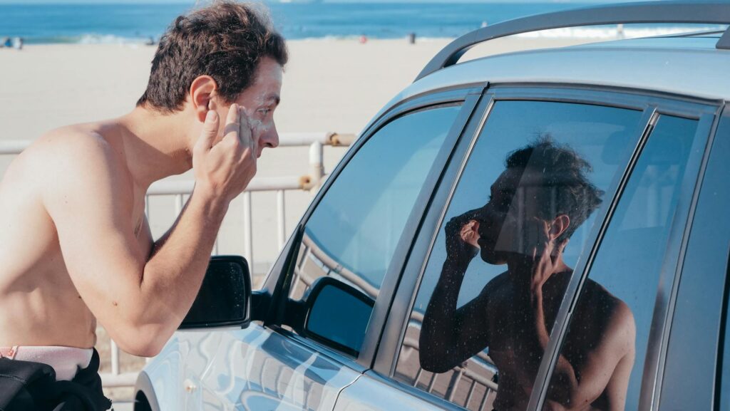 hombre en la playa usa el mejor bloqueador social frente a su auto